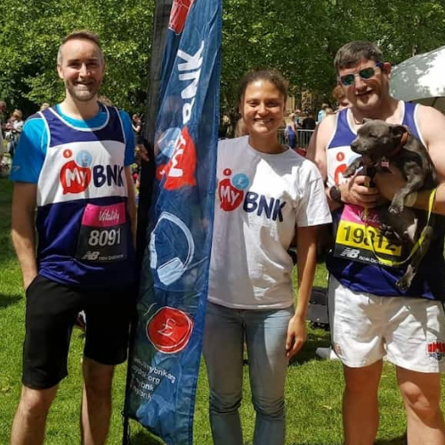 A group of Athletes posing for a shot with one holding a dog