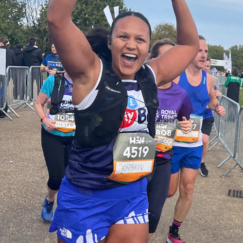 An athletic woman jubilating with a group of athletes running in the background