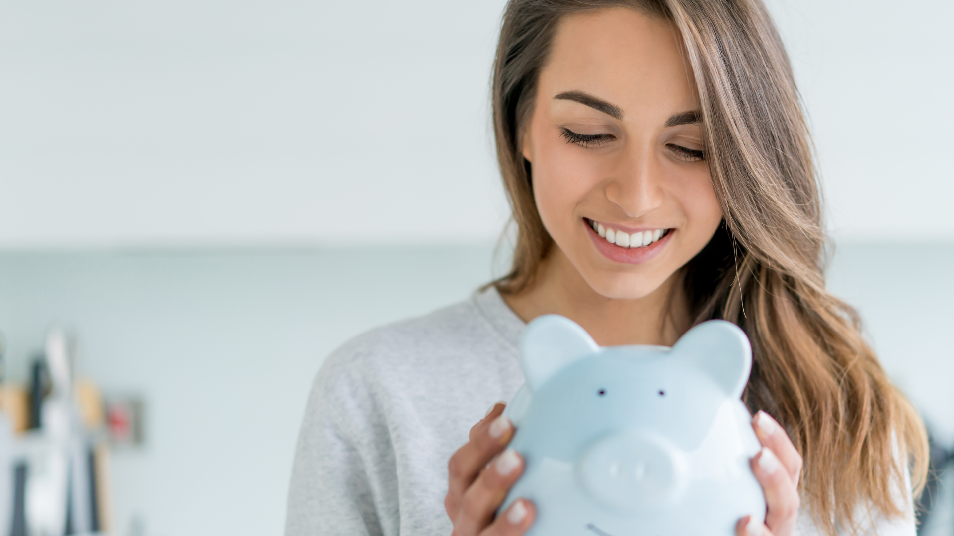 Young woman smiling and holding a piggy bank