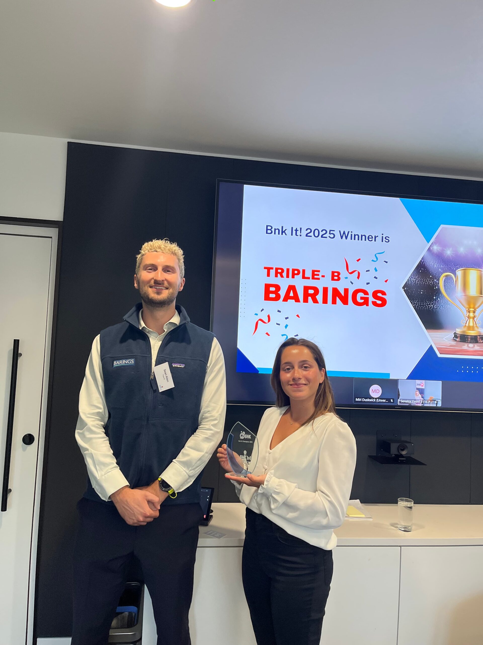 Two Barings colleagues holding a trophy as the 2025 Bnk It winners