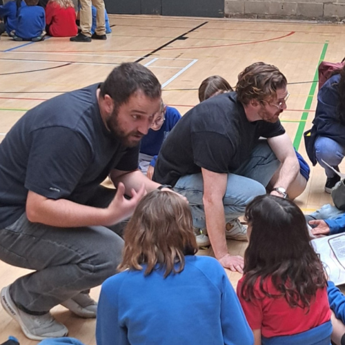 Two volunteers speaking to a group of children