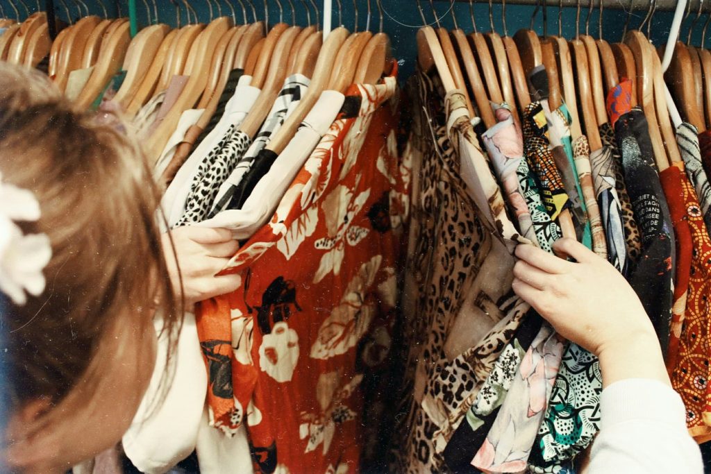 A woman browsing through a thrift shop clothes rail