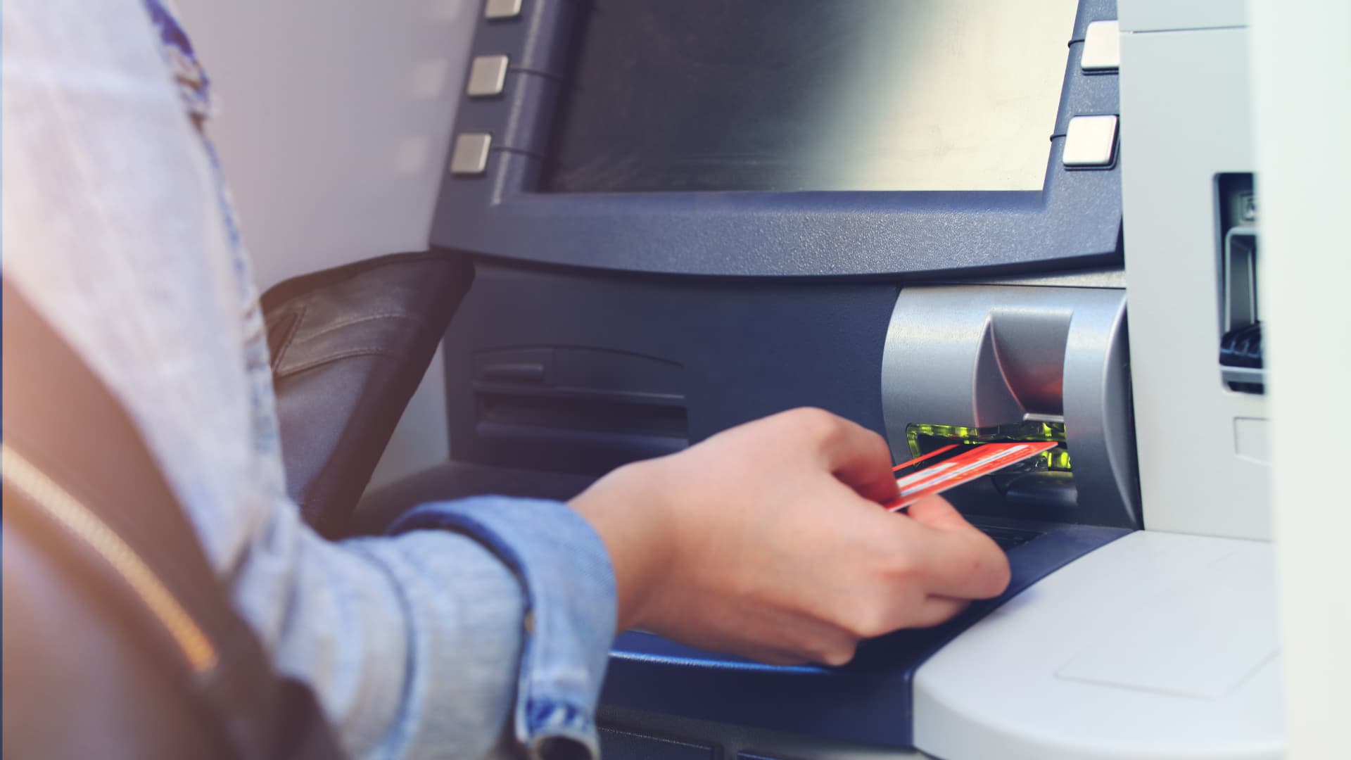 A woman's hand inserting a debit card into an ATM