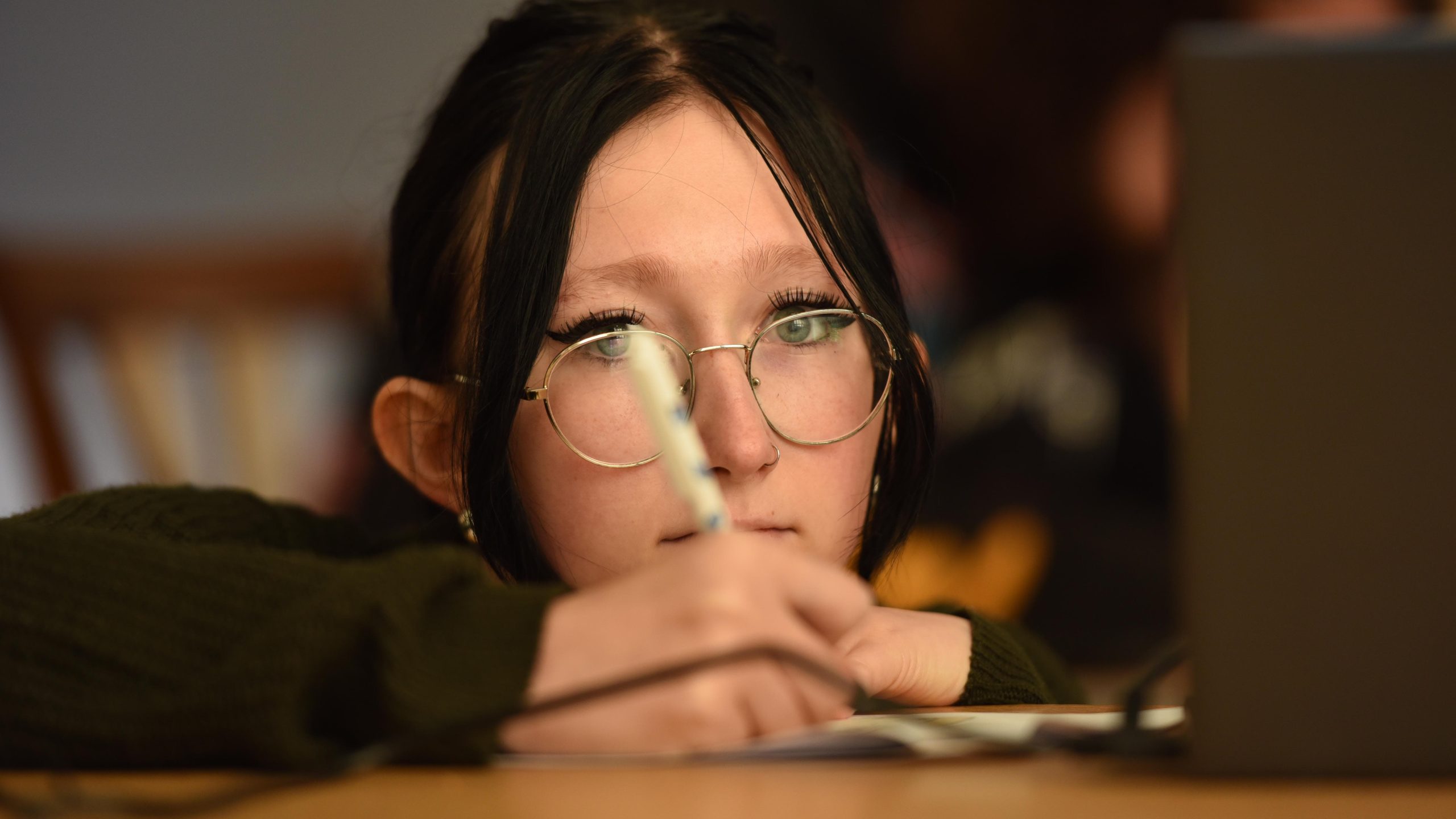 Teenage girl leaning on a table writing with a pen and paper