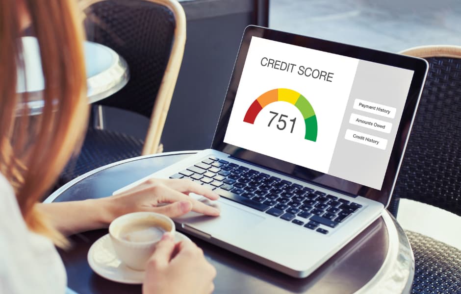 Person looking at laptop with credit score on screen.