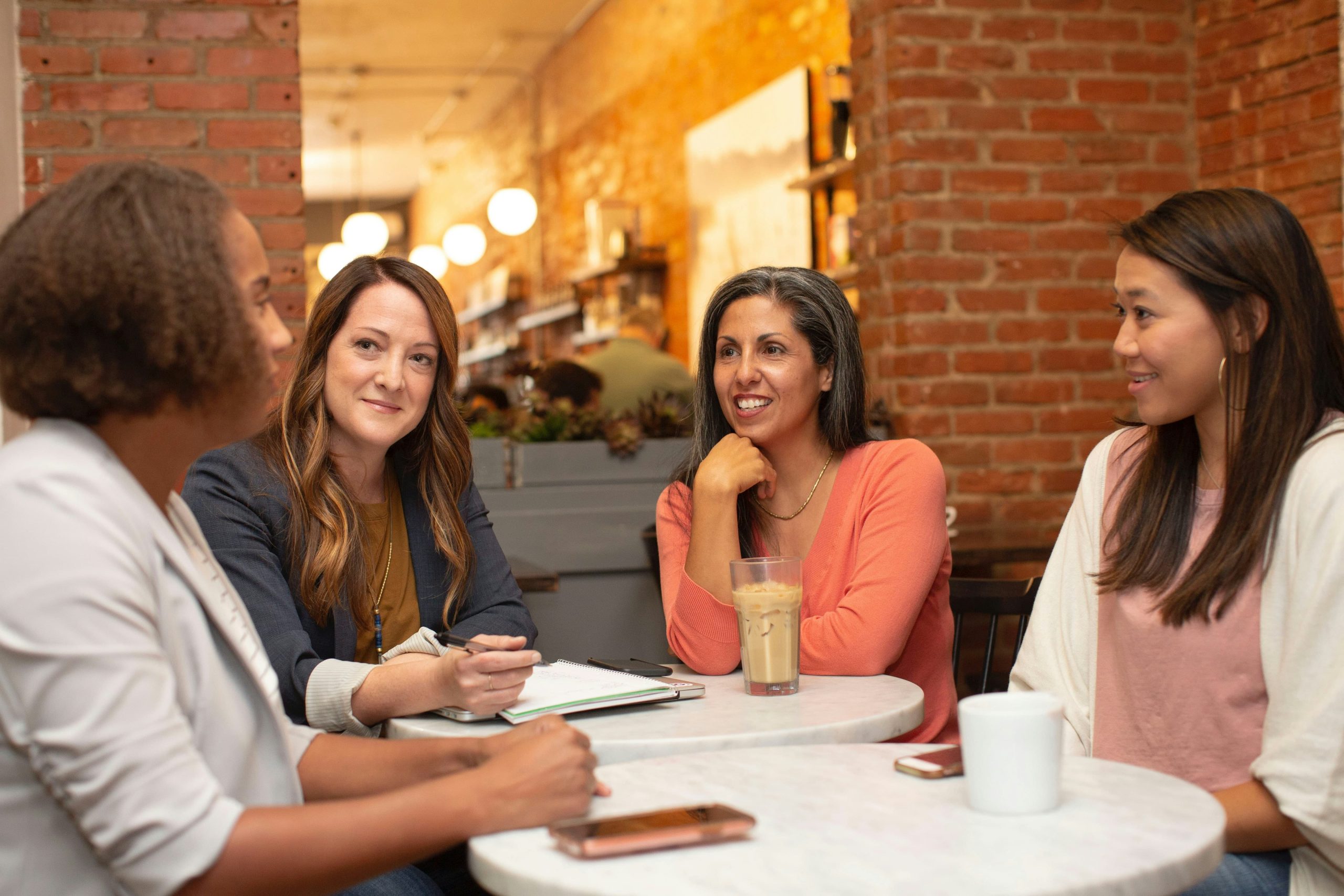 four women sat around a table in a cafe chatting