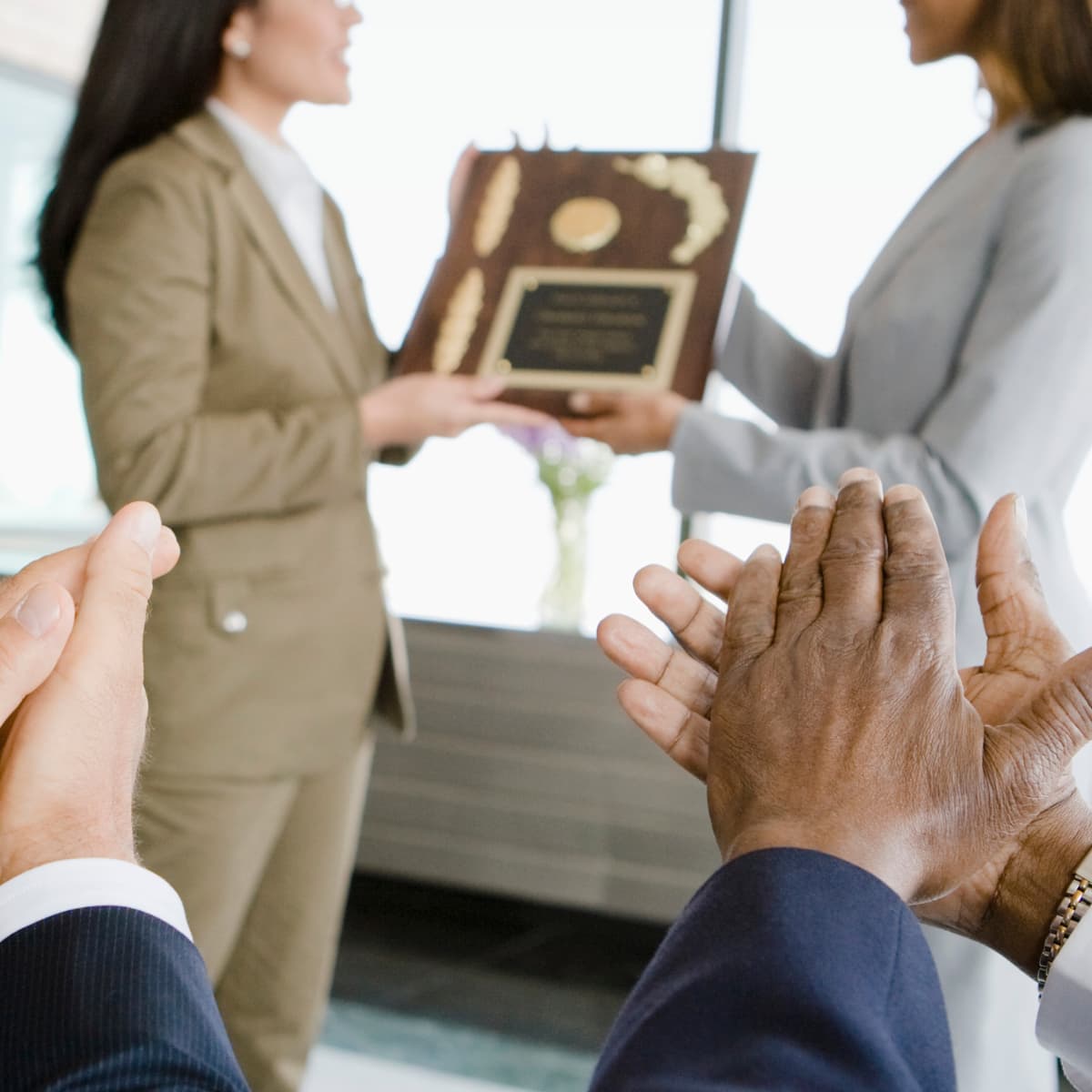 Image of a person receiving an award and two people clapping.