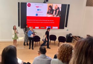 Staff from Money Ready standing next to a screen presenting the Wee Bursary to a room of guests