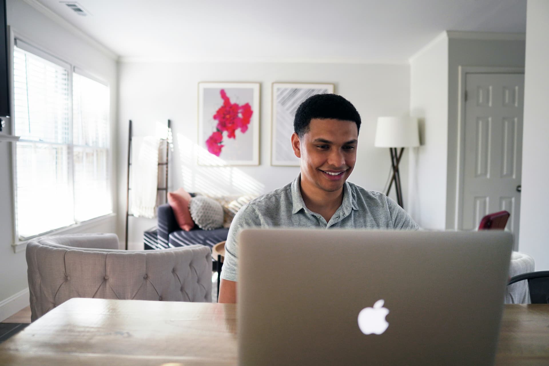 Young man sat at a table in his house with his laptop open