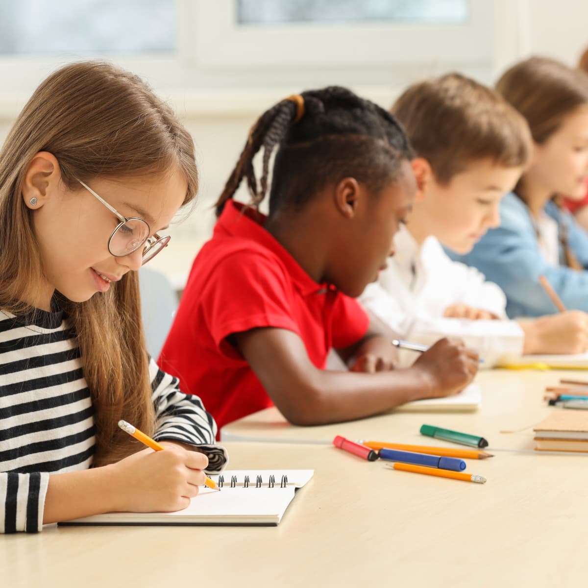 Image of children sitting at a desk and writing