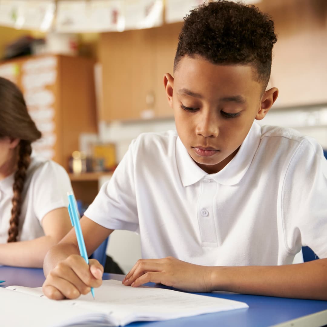 a young boy at primary school writing