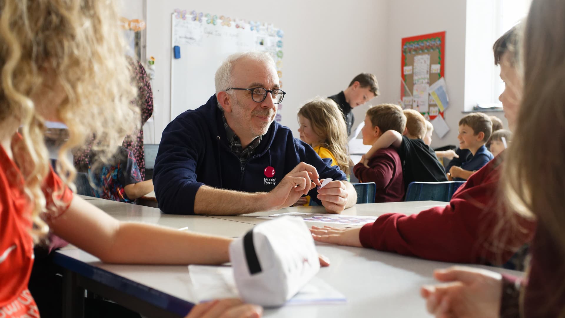 Male trainer teaching primary school pupils about money