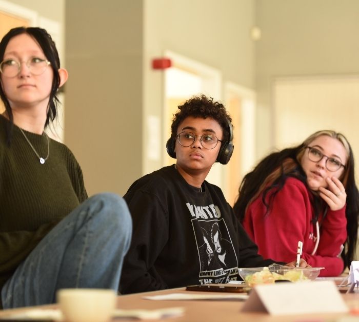 Three young people listening in a workshop.